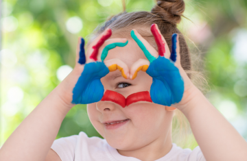 Girl holding up heart with colorful hands